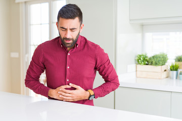Handsome hispanic business man with hand on stomach because indigestion, painful illness feeling...