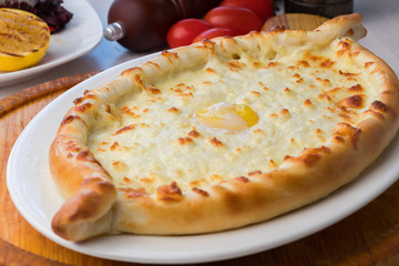 Ajarian hachapuri with cheese and egg on white plate
