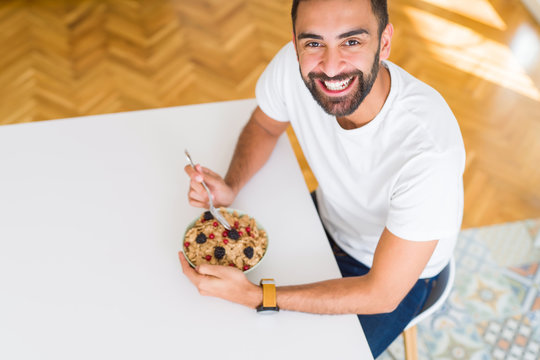 Above angle of handsome man eating healthy cereals for breakfast in the morning