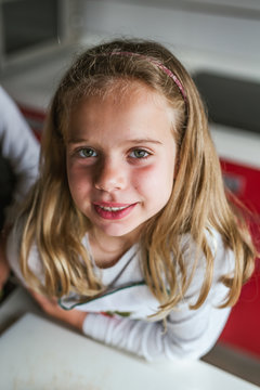 Portrait of cute young girl looking at camera indoors