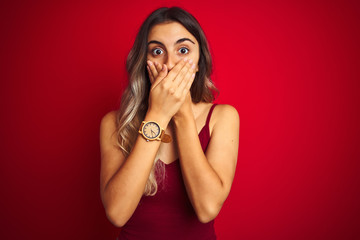 Young beautiful woman wearing a t-shirt over red isolated background shocked covering mouth with hands for mistake. Secret concept.