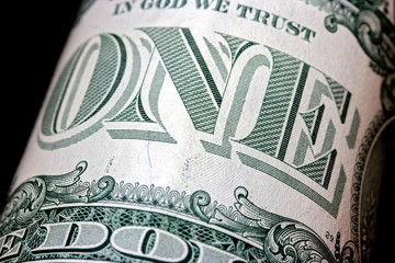 Close-up view of dollar bill. One dollar on black background, macro view.