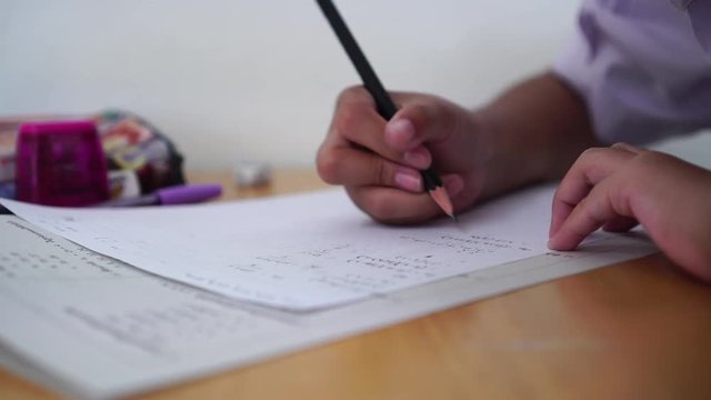 Student taking exams, writing examination on paper answer sheet optical form of standardized test on desk doing final exam in classroom, Education assessment Concept. Soft focus
