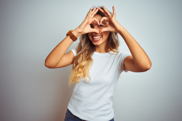 Young beautiful woman wearing casual white t-shirt over isolated background Doing heart shape with...