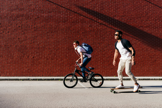 Young African American men riding bicycle and skateboard