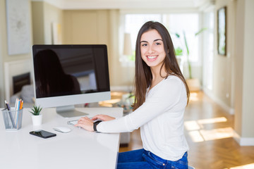 Young woman smiling working using computer and showing a blank screen on the background