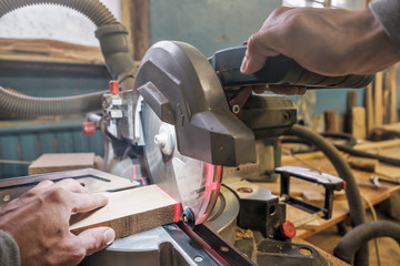Caucasian man carpenter worker working driving circular saw to cut boards on a new furniture detail.