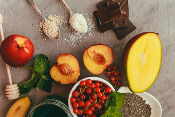 Superfoods and healthy food on a gray background with copy space Fruits: mango, banana, currant, peaches lie next to chia and spirulina seeds Top view Copy space Selective focus