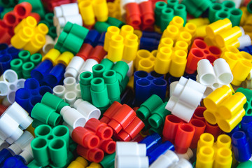 Multicolored plastic building blocks of the designer. Background of plastic colored details building blocks. Parts of bright small spare parts for toys. Close up.