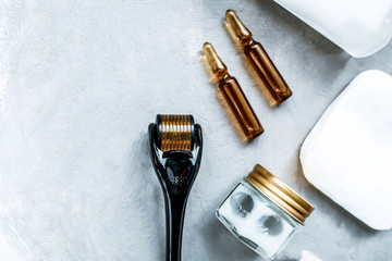 Dermaroller and serum next to an anti aging face cream Beauty industry Close-up  Dermaroller for medical micro needling therapy Derma roller mesoroller for mesotherapy  Copy space Selective focus