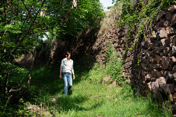 Woman walking on a mountain trail with stone handmade walls.
