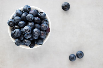 Fresh blueberries in a white bowl on a gray background. Top view.