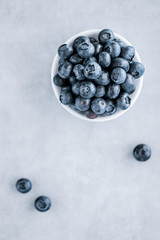 Fresh blueberries in a white bowl on a gray background. Top view.