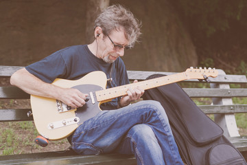 An older male musician playing guitar on a New York City Street