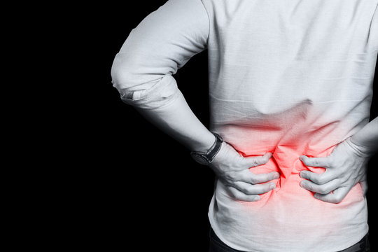 Man suffering from a lower back pain, isolated on black background