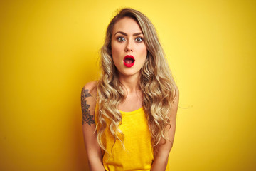Young beautiful woman wearing t-shirt standing over yellow isolated background afraid and shocked with surprise expression, fear and excited face.