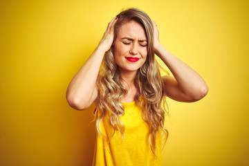 Young beautiful woman wearing t-shirt standing over yellow isolated background suffering from headache desperate and stressed because pain and migraine. Hands on head.