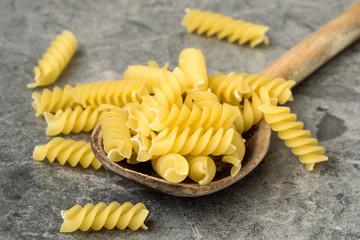 Uncooked pasta in wooden spoon