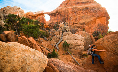 Woman climbing on rock at Arches National Park