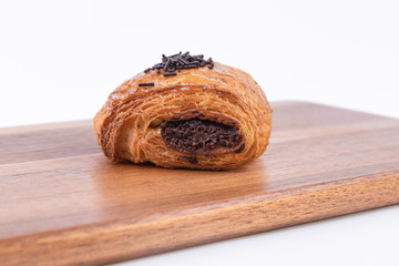 A delicious roll of puff pastry filled with chocolate on a wooden board
