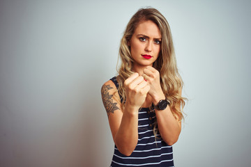 Young beautiful woman wearing stripes t-shirt standing over white isolated background Ready to fight with fist defense gesture, angry and upset face, afraid of problem