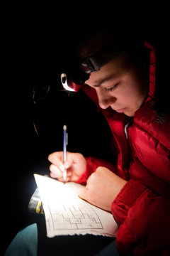 A woman does sudoku puzzles by headlamp.