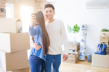 Young asian couple smiling taking a selfie photo with smartphone, moving to a new home together