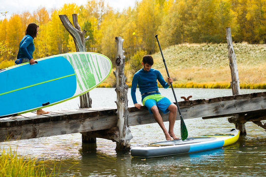 A man and a woman prepare their inflatable stand up paddle boards for SUPing in an alpine lake in the San Juan Mountains, Colorado in autumn.