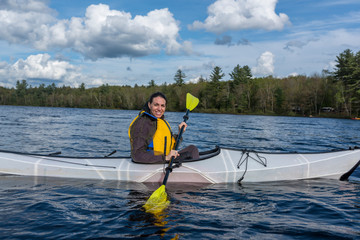 woman smiling while paddling inside of a white kayak