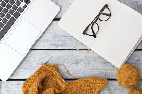 Women's hobby. Crochet and knitting. Working space.  Cup of coffee , balls of mustard yarn, needles, knitwear, crochet hooks on the wood table in the cozy home. - Powered by Adobe