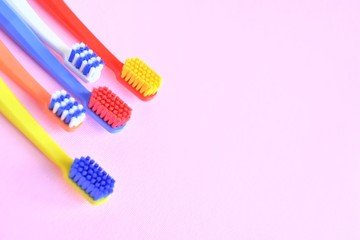 Row of Colorful toothbrushes with selective focus on blurred pink background. Dental tools for daily teeth protection. Multicolored plastic toothbrush with bright bristles with soft focus. Oral hygien