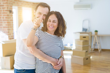 Middle age senior romantic couple holding and showing house keys smiling happy for moving to a new home