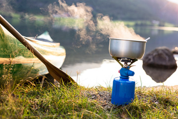 Oppstrynsvatnet Lake, Stryn, Nordfjord, Norway: Oatmeal cooking by the lake with the rising sun and a canoe in the background.