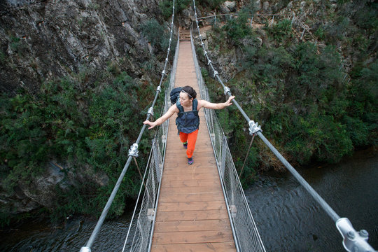 A woman wearing a pack hikes across the hanging bridges in the beautfiul limestone canyons near Chulilla, Spain.