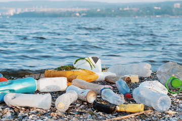 Spilled garbage on the beach of a big city. Empty used dirty plastic bottles, children's plastic...
