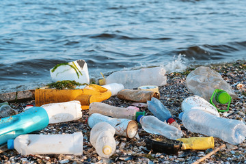 Spilled garbage on the beach of a big city. Empty used dirty plastic bottles, children's plastic toys. Dirty sea, sandy coast the Black Sea. Environmental pollution. Ecological problem. Moving waves