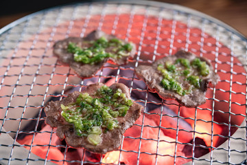 japanese barbeque beef tongue with green onion on charcoal grill