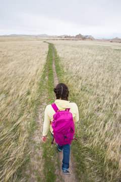 A woman  hiking along the scenic 5 mile Castle Trail in Badlands National Park. It is one of the few developed trails in the park and meanders through prairie grass and the unique soil and rock formations in the Cedar Pass area.