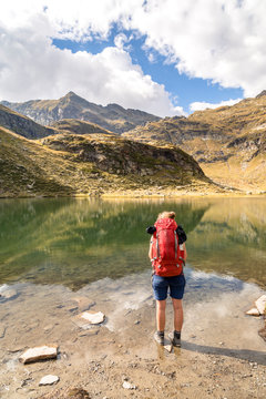 Spronser Lakes Hike, South Tyrol, Italy: A female hiker resting standing in the water at Lago di Vizze / Pfitscher Lacke, one of the Spronser lakes.