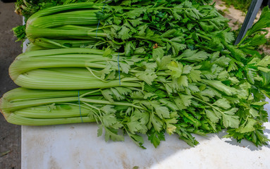 Selection of whole celery for sale on a market stall.