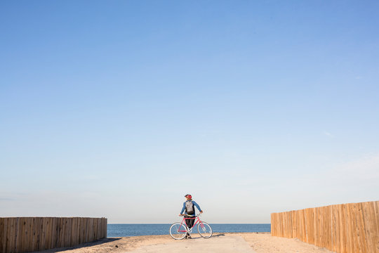 Playa del Rey, Los Angeles, California, USA: A young woman with her red single speed bike standing at the bach and looking out over the ocean.