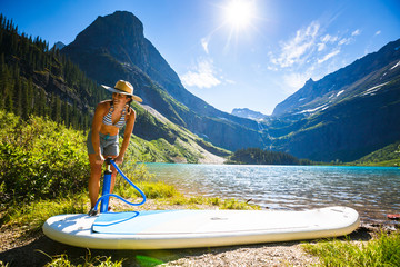 Woman pumping up paddleboard by Grinnell Lake