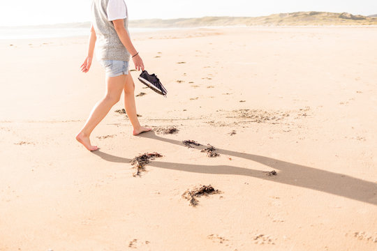 Tramore Beach, Kiltooris, Portnoo, Donegal, Ireland: A woman walking along the beach in the evening light.
