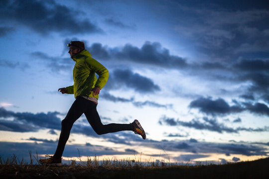 A male runner wearing a headlamp running at dusk in north Idaho.