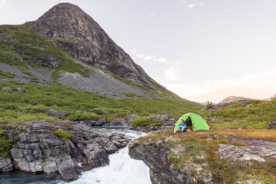 Eidsdalselva, M&macr;re og Romsdal, Norway: A male hiker at his camp on a cliff by the river.