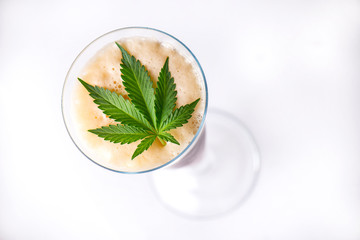 Detail of cold glass of beer with cannabis leaf isolated over white