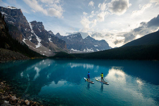 A couple stand up paddle board at Moraine Lake in Banff National Park in Canada.