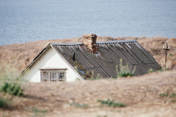lonely old retro house with roof on blue sea shore in autumn