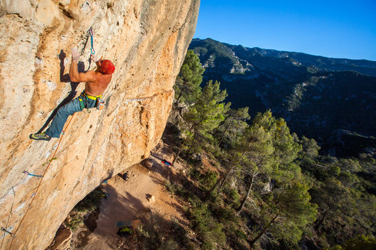 A man on Telemaster (8a/5.13b) at the Raco de les Espadelles sector at Margalef, Spain at sunset.