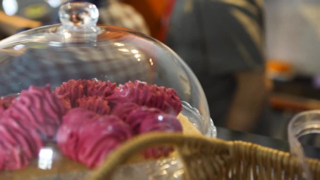 Close up for pink meringue cakes under the glass loche at french cafe patisserie, food concept. Art. Beautiful pink cakes lying on a tray on blurred background.